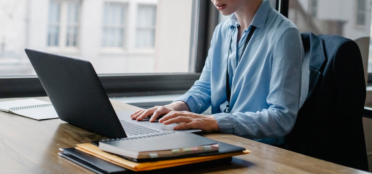 Services Young businesswoman working on a laptop in an office setting, demonstrating productivity and focus.